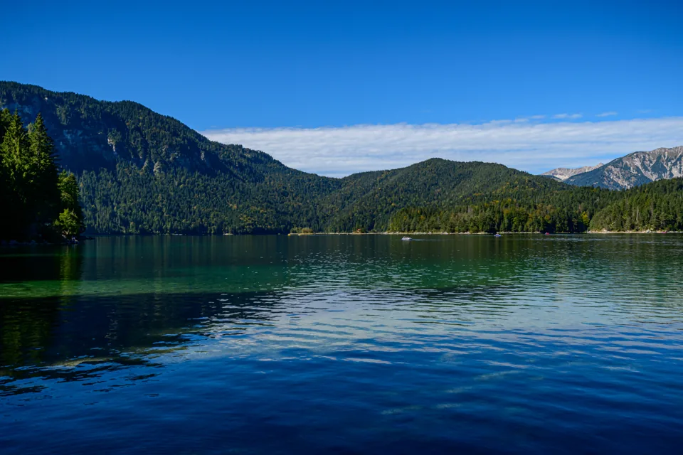 Türkisgrüner Eibsee mit bewaldeten Inseln und den Bergen der bayerischen Alpen.